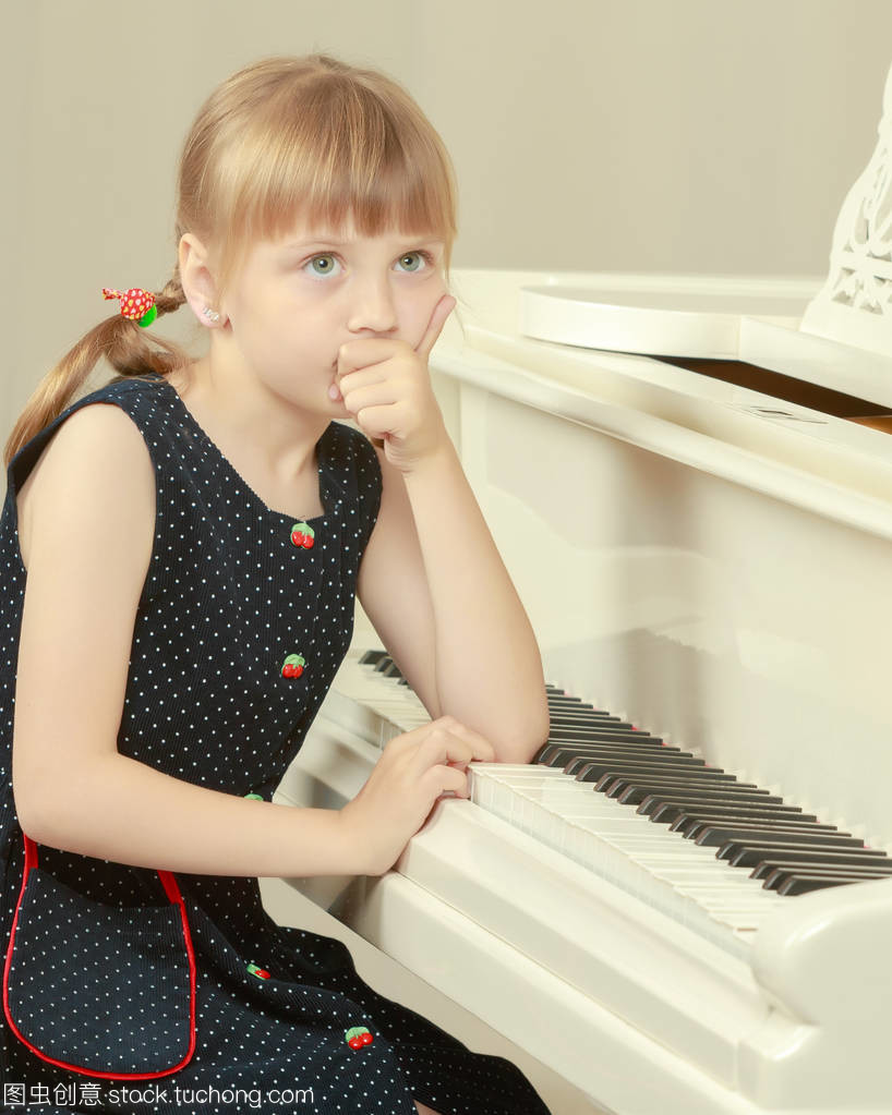 漂亮的小女孩正在玩一架白色的大鋼琴